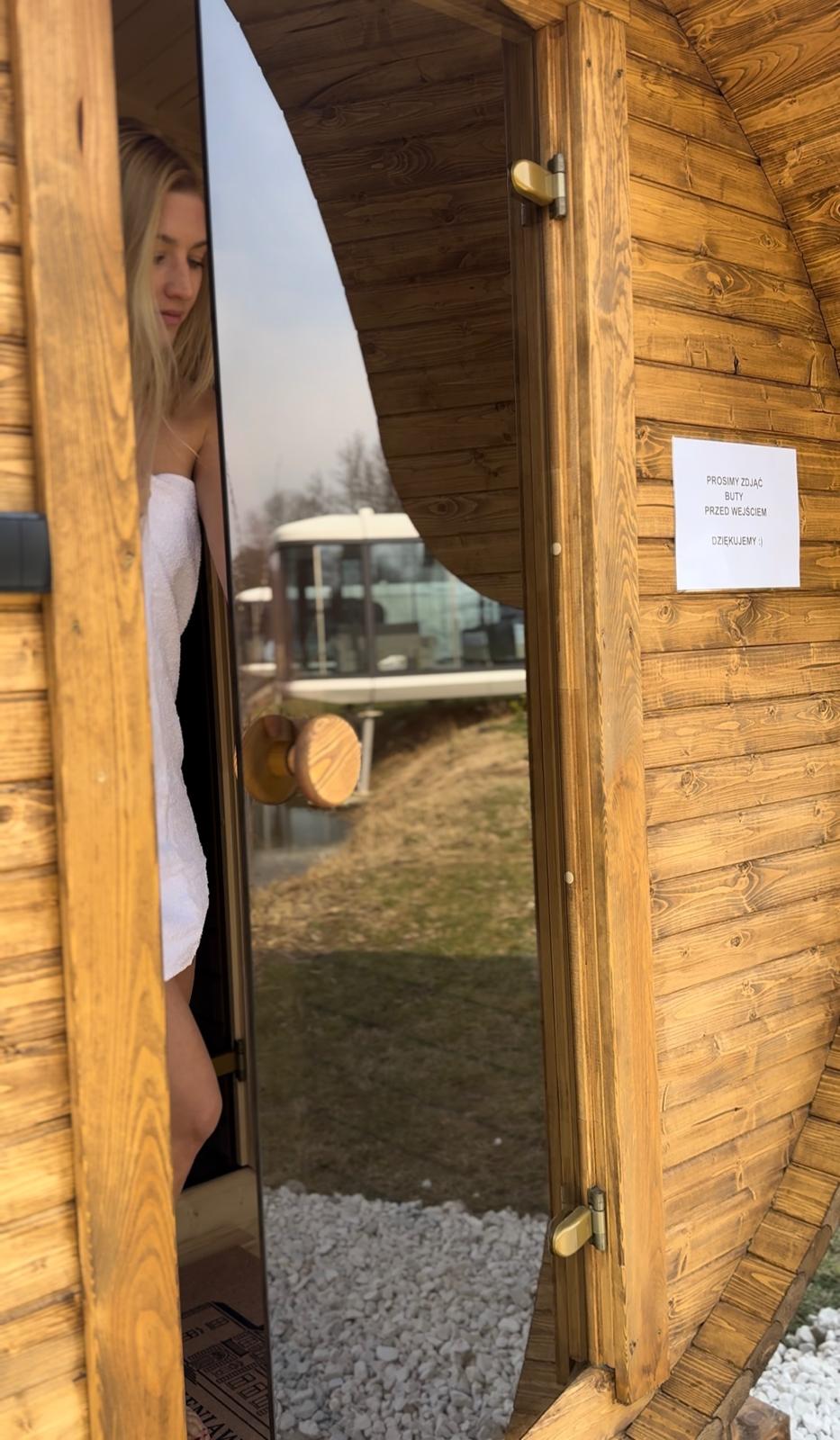 Wejście do sauny beczkowej z tabliczką o konieczności zdjęcia obuwia